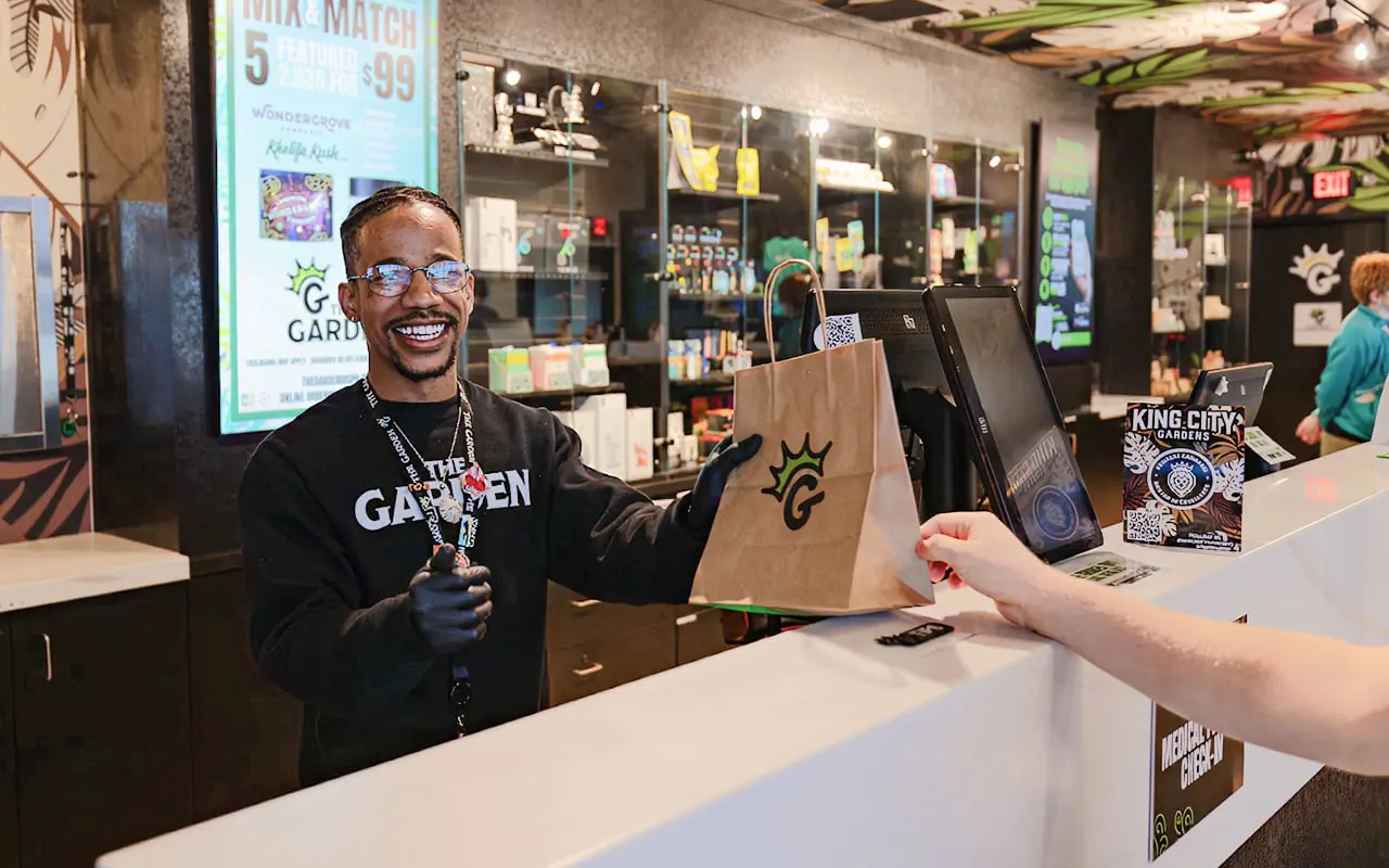 A Garden budtender at the Sycamore Township counter beneath the jungle-print ceiling