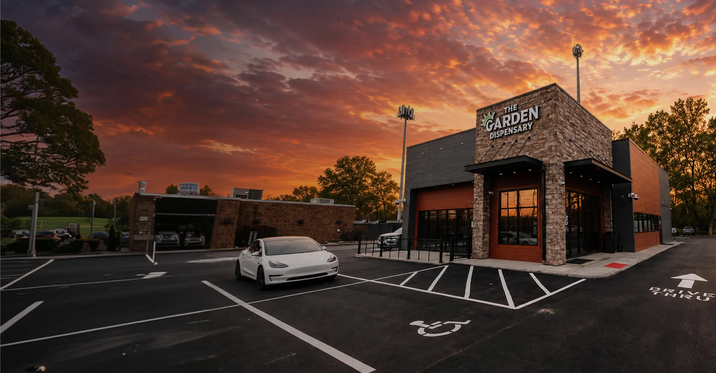 The Garden Dispensary in Sycamore Township at sunset: the stone and cedar storefront on Montgomery Road with the drive-thru lane marked on the lot